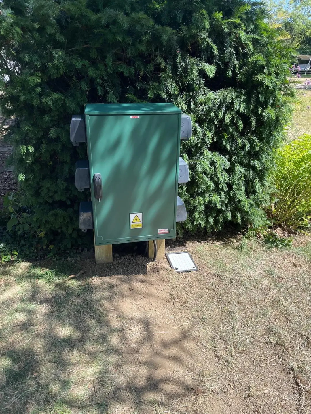 Green outdoor electrical cabinet with weatherproof sockets mounted along both sides