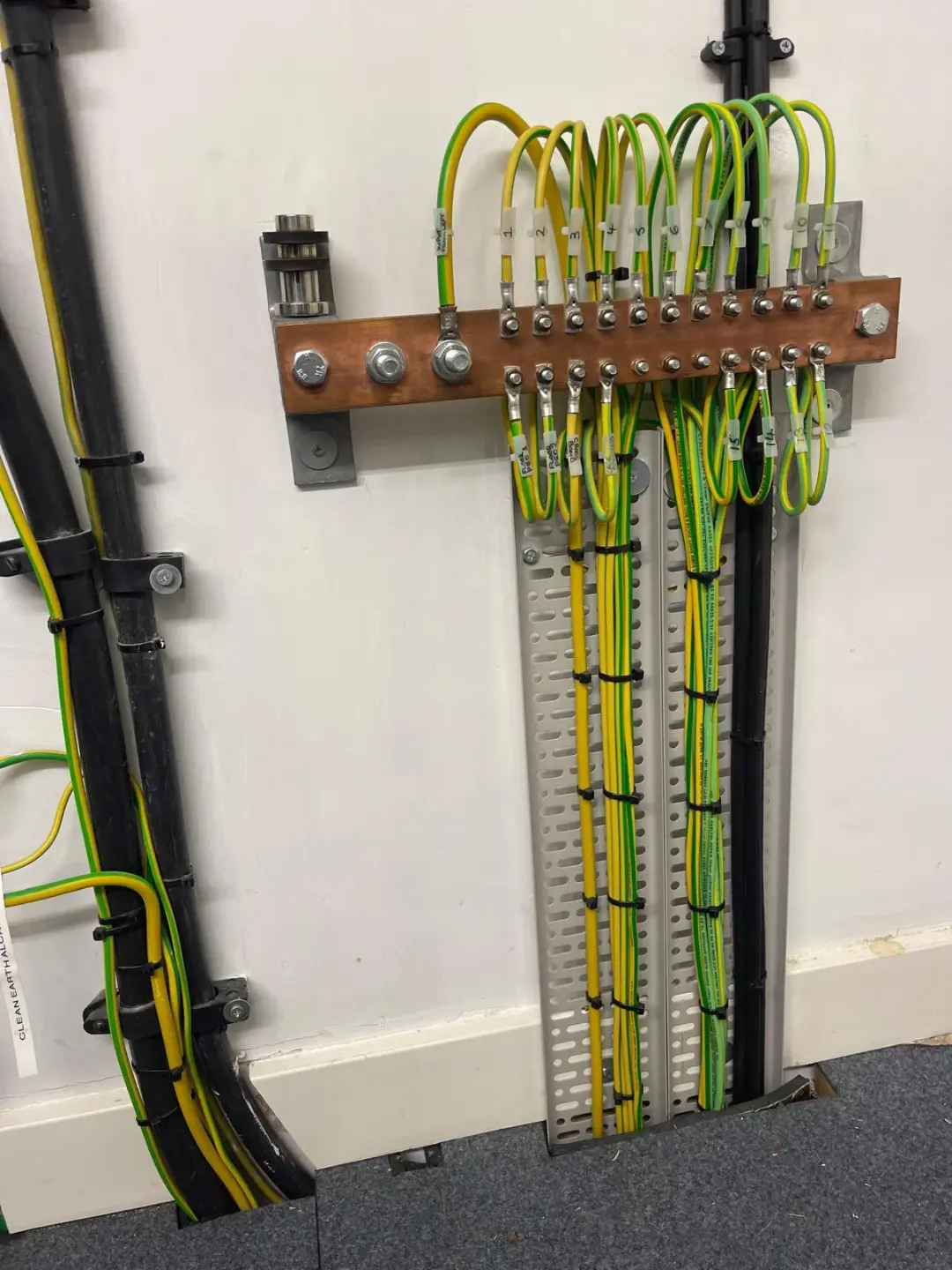 Copper earth bar with numbered green and yellow conductors secured to a cable tray