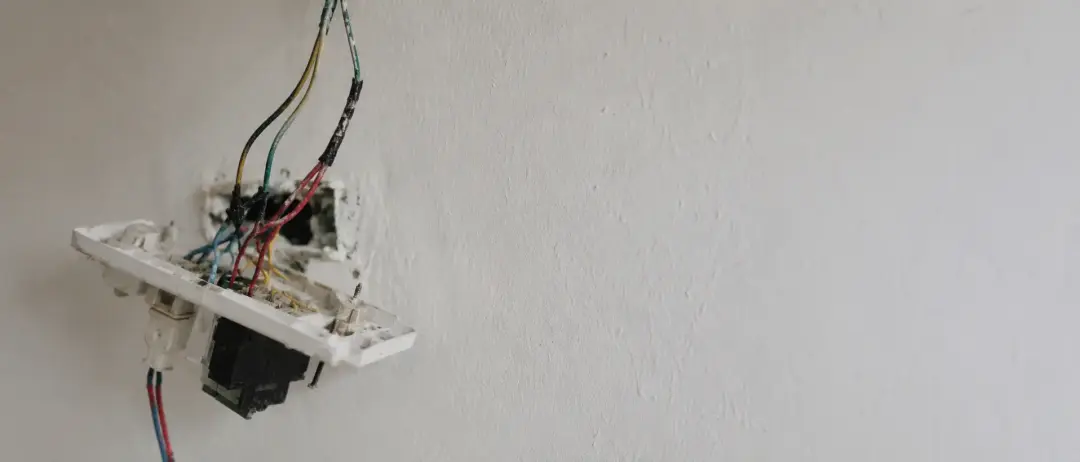 Exposed wiring behind a removed wall fitting